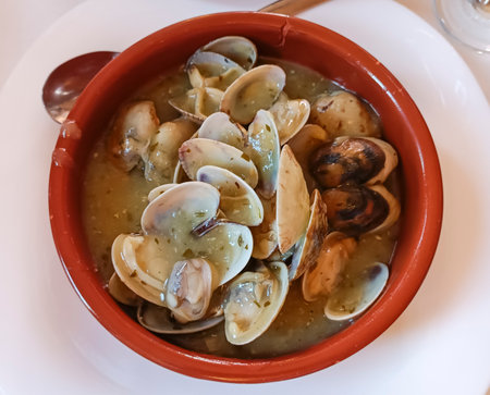 Delicious portion of clams in seafood sauce served in a clay pot in a restaurantの写真素材