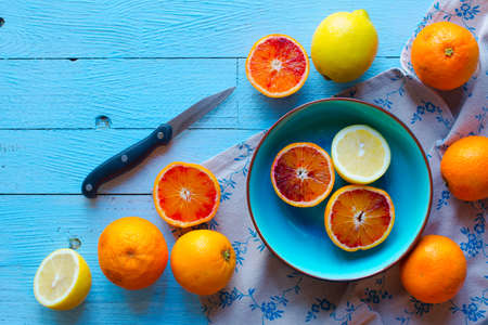 Colorful Orange fruits over a light blue painted wood table with a simmetric position.