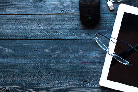 Dramatic and Dark Light Filtered Office desktop with a lot of objects including a smartphone, a...
