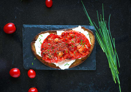 Delicious Tasty Avocado Eggs and Tomato Cheese Toasts over a stone plate with an old look wooden background and dramatic light.の写真素材