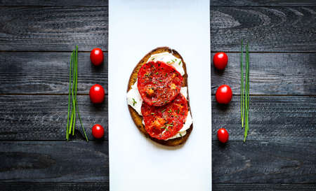 Delicious Tasty Avocado Eggs and Tomato Cheese Toasts over a stone plate with an old look wooden background and dramatic light.の写真素材