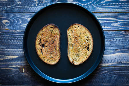 Food composition made of 2 slices of toasted bread in a black pan over an old look vintage wood background.の写真素材