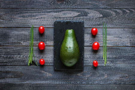 Veggie Food composition with half avocado over a darkdish and a wood distressed old background. Dramatic light.の写真素材