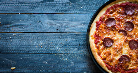 Tasty Hand Made Tomatoes and Pepperoni Pizza with italian style recipe over a wooden table with a Dramatic light.の写真素材
