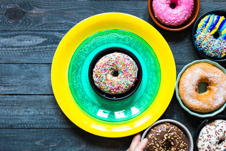 Colorful Donuts breakfast composition with different color styles of doughnuts over an aged wooden desk background.の写真素材