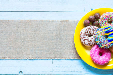 Colorful Donuts breakfast composition with different color styles of doughnuts over an aged wooden desk background.の写真素材