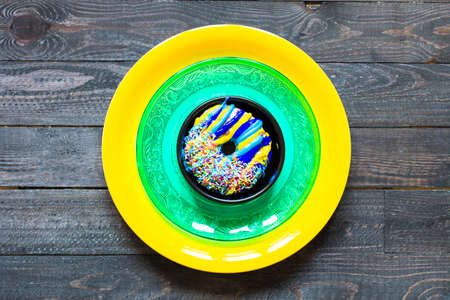 Colorful Donuts breakfast composition with different color styles of doughnuts over an aged wooden desk background.の写真素材