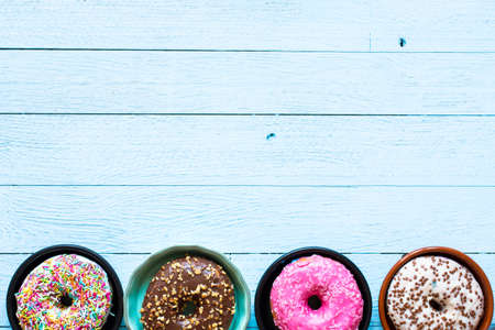 Colorful Donuts breakfast composition with different color styles of doughnuts over an aged wooden...