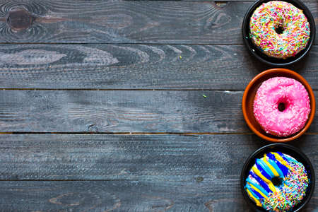 Colorful Donuts breakfast composition with different color styles of doughnuts over an aged wooden desk background.の写真素材