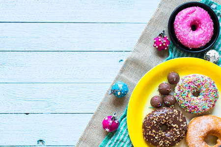 Colorful Donuts breakfast composition with different color styles of doughnuts over an aged wooden desk background.の写真素材