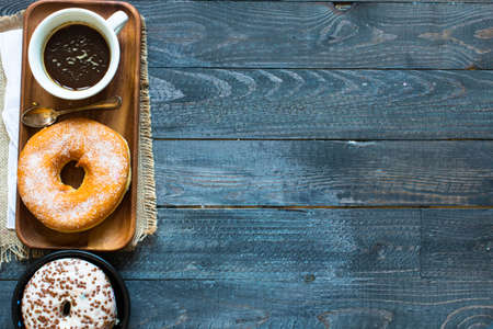 Colorful Donuts breakfast composition with different color styles of doughnuts and fresh coffee on the side over an aged wooden desk background.の写真素材