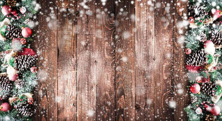 Merry Christmas Frame with Snow and real wood green pine, colorful baubles, knots with berries and other seasonal stuff over an old wooden aged backgroundの写真素材