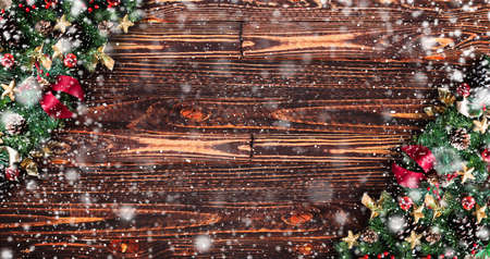 Merry Christmas Frame with Snow and real wood green pine, colorful baubles, knots with berries and other seasonal stuff over an old wooden aged backgroundの写真素材