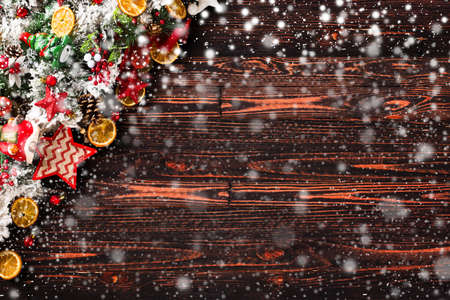 Merry Christmas Frame with Snow and wood green pine, colorful baubles, knots with berries,stars, orangesand other seasonal stuff over an old wooden aged backgroundの写真素材