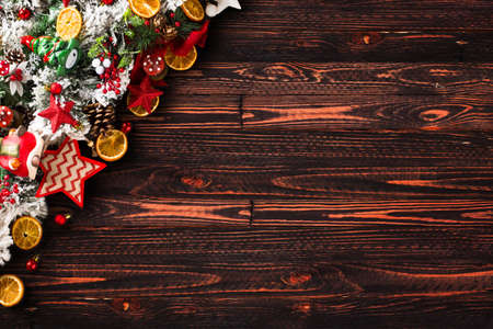 Merry Christmas Frame with green pine, colorful baubles, knots with berries,stars, orangesand other seasonal stuff over an old wooden aged backgroundの写真素材