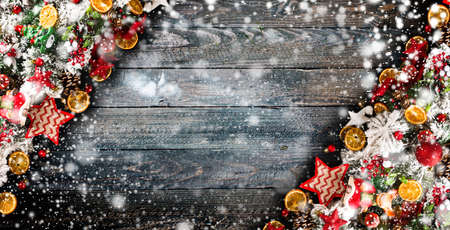 Merry Christmas Frame with Snow and wood green pine, colorful baubles, knots with berries,stars, orangesand other seasonal stuff over an old wooden aged backgroundの写真素材
