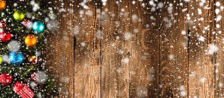 Merry Christmas Frame with Snow and real wood green pine, colorful baubles, knots with berries and other seasonal stuff over an old wooden aged backgroundの写真素材