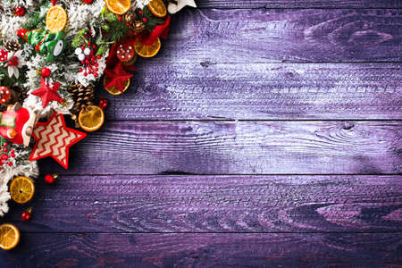 Merry Christmas Frame with green pine, colorful baubles, knots with berries,stars, orangesand other seasonal stuff over an old wooden aged backgroundの写真素材