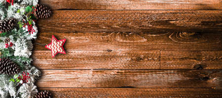 Merry Christmas Frame with green pine, colorful baubles, knots with berries,stars and other seasonal stuff over an old wooden aged backgroundの写真素材