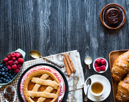 Top view of a wood table full of cakes, fruits, coffee, biscuits, spices and more breakfast classic sweet foods.の写真素材