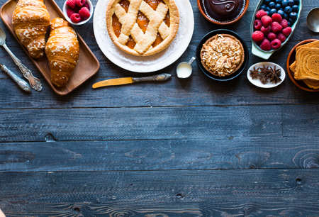 Top view of a wood table full of cakes, fruits, coffee, biscuits, spices and more breakfast classic sweet foods.の写真素材