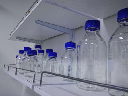 Collection of glass bottles, schott, blue screw cap, for storing liquids, on the shelf of an organized laboratoryの写真素材