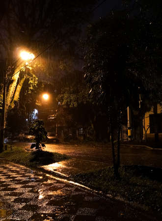 Dark road wet from water due to a heavy storm with reflections of faint yellow lights. Mystery foggy night.のeditorial素材