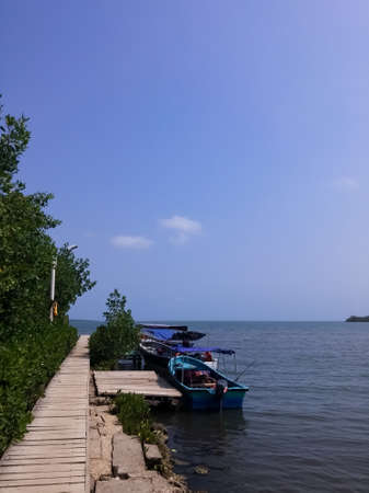 Small blue motor boats anchored to a wooden pier for tourist trips in a tropical blue seaのeditorial素材