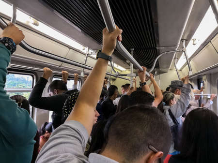 Interior of a metro car of the Medellin Metro, Colombia. Crowded with people sitting or standing.のeditorial素材