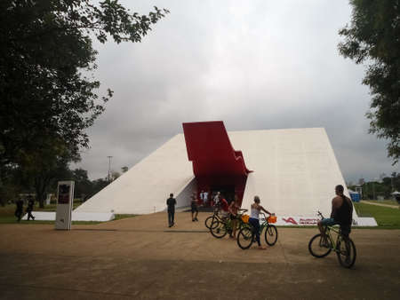 Cyclists located at the entrance of the Ibirapuera Auditorium, in the Ibirapuera urban park in Sao Paulo, Brazil. Modernist architecture by Oscar Niemeyer. Concept of relaxation, culture, entertainment and sport.のeditorial素材