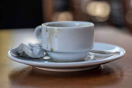 Cup of coffee and sugar pack on a wooden table in a barの写真素材