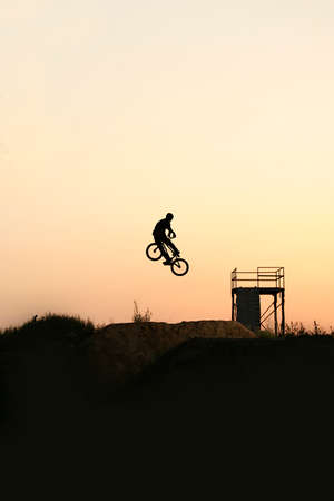 Silhouette of a young rider on a bike in the bike park.の写真素材