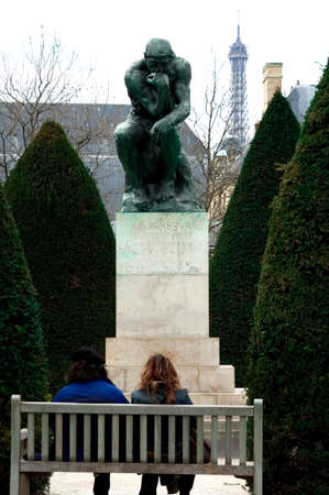 couple sitting in front of Rodin's Thinker with Eiffel Tower in background, Parisのeditorial素材