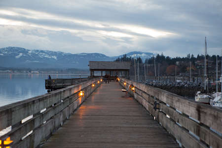 couple walking along Comox harbour walkway at dusk, Vancouver Island, BC, Canadaのeditorial素材