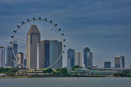 The Skyline of Singapore business district with a big ferris wheel in the foreground.のeditorial素材