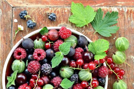 Garden berries in a bowl on wooden background. Top view.の写真素材