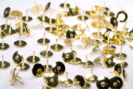 Brass thumb tacks scattered against a white background.の写真素材