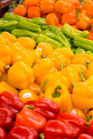 Piles of red, yellow, and orange peppers at the local grocery store. Focus on the yellow peppers.の写真素材