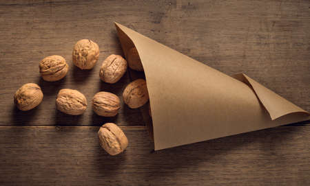 Paper cone with walnuts on wooden table
