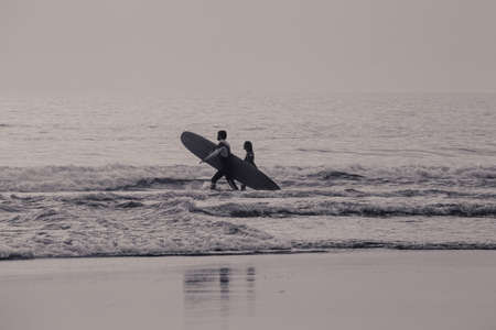 COUPLE OF SURFER ENTERING THE WATER TO TAKE THE WAVESの写真素材