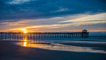 sunset at the north carolina beach with atlantic beach pier and sunrise with sand and water in the foregroundの写真素材