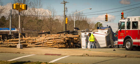 Overturned logging truck with work men and fire engineのeditorial素材