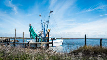 Fishing boat with green nets and outriggers docked on the NOrth Caroina coast with sunes in the...