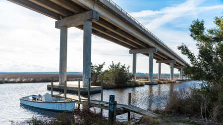 Small wooden Fishing Boat at wooden dock under modern bridgeの写真素材