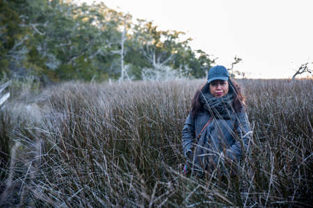 Woman stanidn in tall reed grassの写真素材