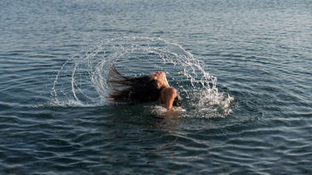 teen flipping hair in water and making a splash