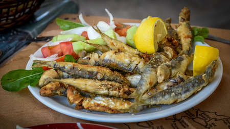 Fried smelt fish on a plate with saladの写真素材