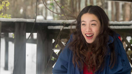 Young asian teen with red dress standing in snow surprised and smiling