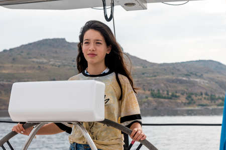 Young teen girl at he helm of a sailboat off the coast of Petra, Lesvos