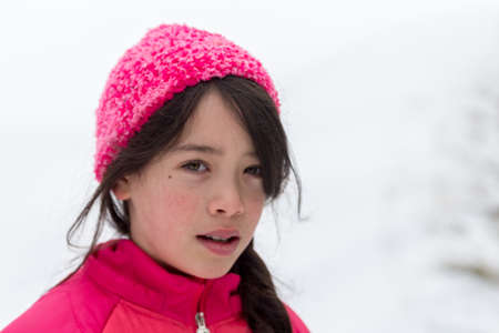Young Asian girl with pink hat and jacket in snow